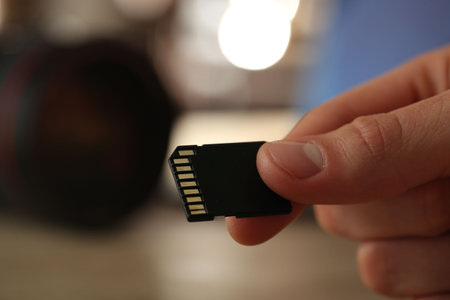 Man with SD memory card on blurred background, closeup. Space for textの写真素材