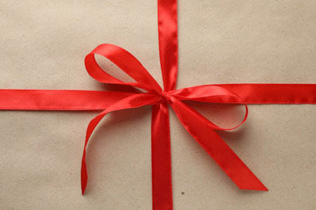 Gift wrapped in kraft paper and bow as background, top viewの写真素材