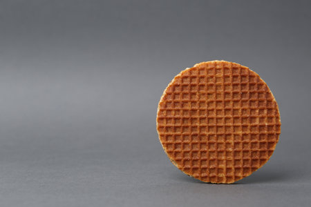 One tasty round waffle on gray background. Space for textの写真素材