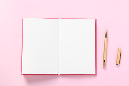 Open blank notebook and pen on pink background, flat layの写真素材