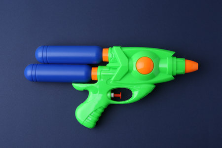Bright plastic water gun on dark blue background, top viewの写真素材