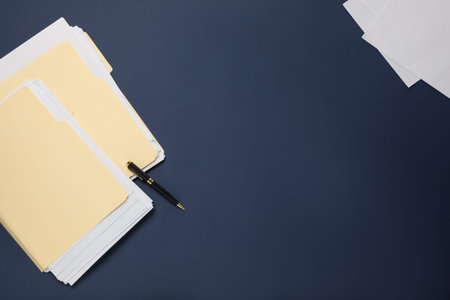 File folders with papers and pen on dark blue background, flat lay. Space for text