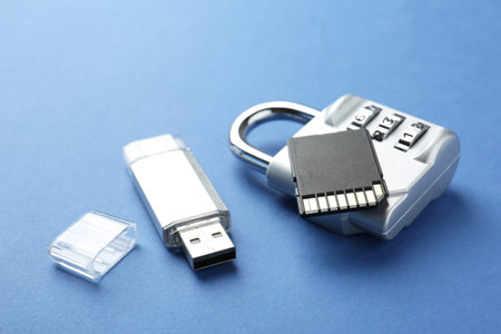 Flash drive, SD memory card and combination padlock on blue background, closeup