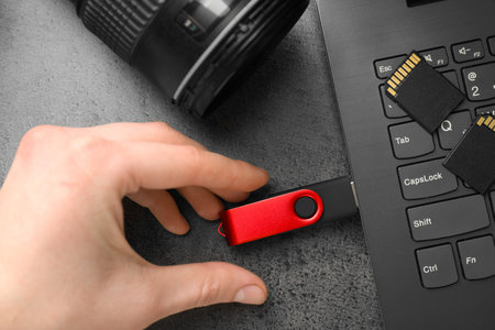 Man inserting modern flash drive at gray table, top view