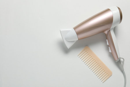 Hair dryer and comb on white background, top view. Space for textの写真素材