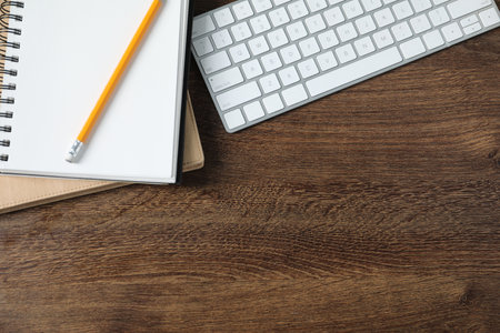 Office supplies and keyboard on wooden table, flat lay. Space for textの写真素材
