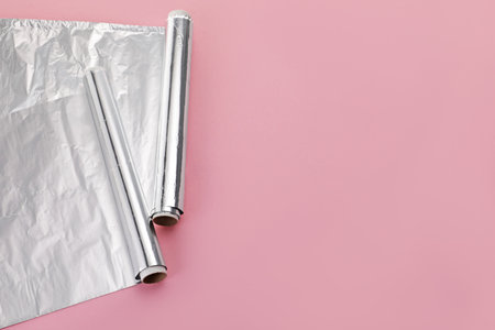 Rolls of aluminum foil on pink background, above view. Space for textの写真素材