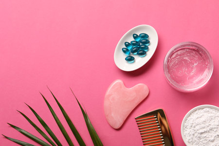 Collagen capsules, powder, gel, comb and gua sha on pink background, flat lay. Space for textの写真素材