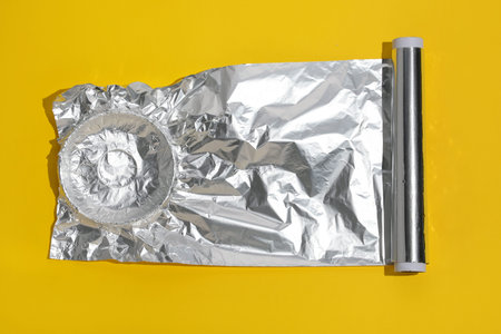 Roll of aluminum foil on yellow background, top viewの写真素材