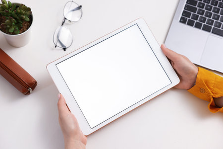 Woman with tablet at white desk indoors, closeup