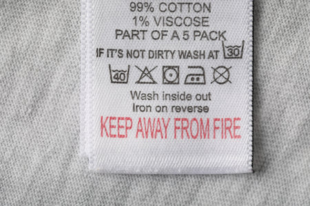 Clothing label with material content and care symbols on gray garment, top viewの写真素材