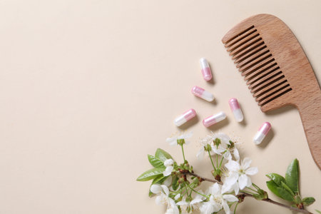 Collagen capsules, blossoms and comb on beige background, flat lay. Space for textの写真素材