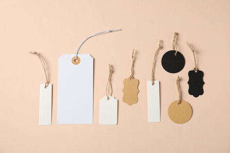 Blank tags with strings on beige background, flat layの写真素材