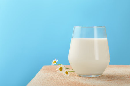 Fresh milk in glass on table against light blue background, closeupの写真素材