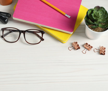 Flat lay composition with office supplies and houseplant on light wooden table. Space for textの写真素材
