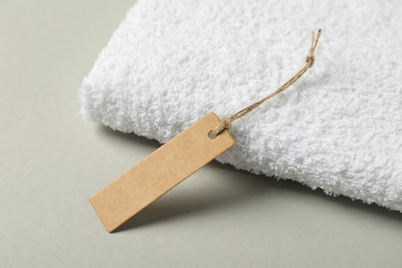Blank tag with string and terry towel on gray background, closeupの写真素材