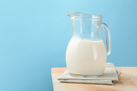 Fresh milk in jug on table against light blue background, closeupの写真素材