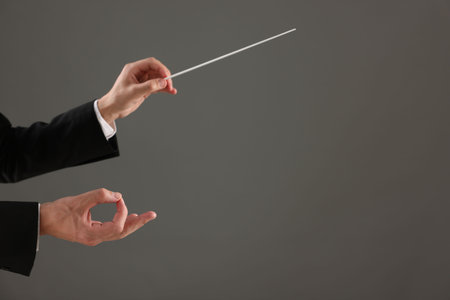 Professional conductor with baton on gray background, closeup. Space for textの写真素材
