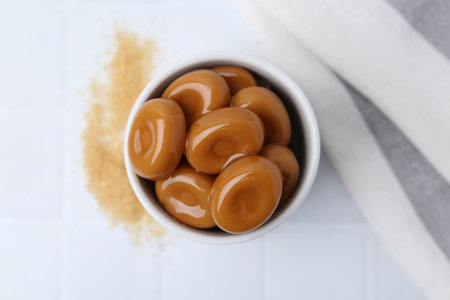 Tasty sweet caramel candies on white tiled table, top viewの写真素材