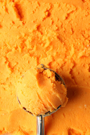 Scoop with tasty orange sorbet as background, top viewの写真素材