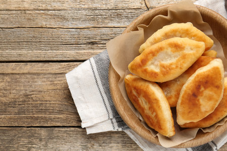 Delicious fried pyrizhky (stuffed pies) on wooden table, top view. Space for textの写真素材