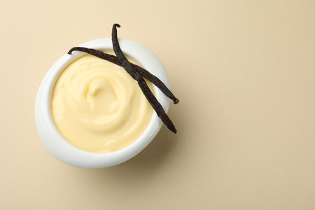 Tasty vanilla pudding with pods on beige background, top view. Space for textの写真素材