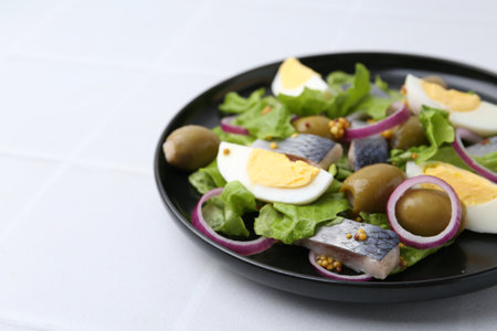 Delicious salad with herring, egg, mustard and vegetables on white tiled table, closeup. Space for textの写真素材