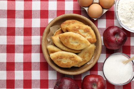 Delicious fried pyrizhky (stuffed pies) and ingredients on table, flat lay. Space for textの写真素材