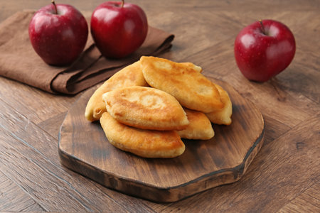 Delicious fried pyrizhky (stuffed pies) and apples on wooden table, closeupの写真素材