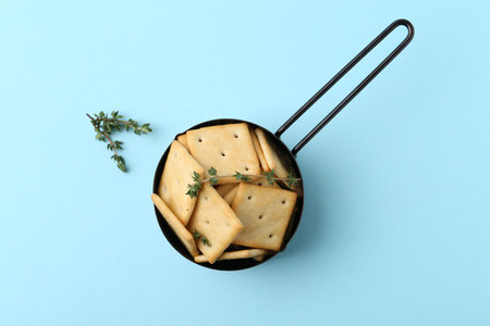 Tasty salty crackers and thyme on light blue background, top viewの写真素材