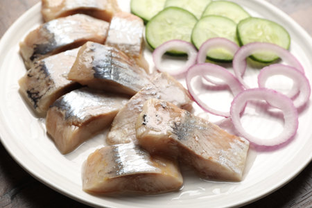 Pieces of delicious herring, onions and cucumber slices on table, closeupの写真素材