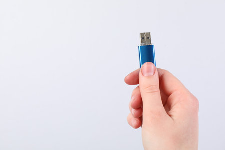 Man with modern flash drive on light gray background, closeup. Space for text