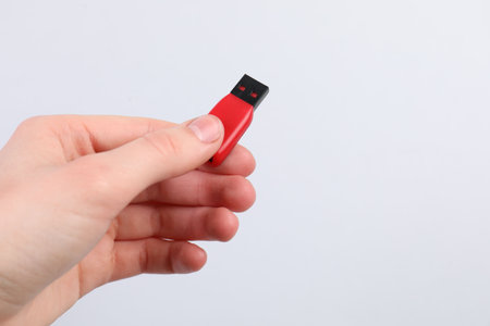 Man with modern flash drive on light gray background, closeup. Space for text