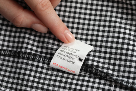 Woman holding clothing label of garment, closeup