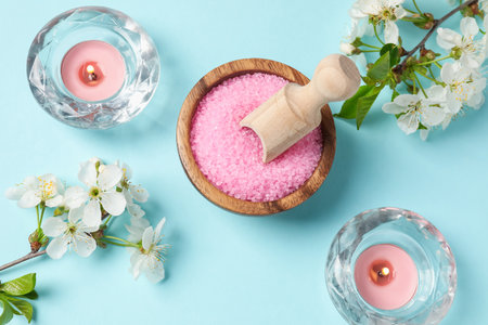 Spa composition with sea salt, burning candles and beautiful flowers on light blue background, flat layの写真素材