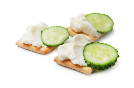 Tasty crackers with cream cheese and cucumber isolated on whiteの写真素材
