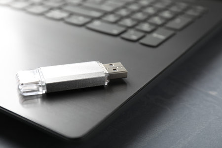 Usb flash drive and laptop on gray textured table, closeup