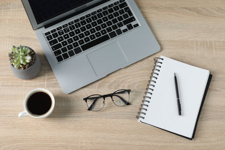Flat lay composition with office supplies, laptop and cup of coffee on wooden table