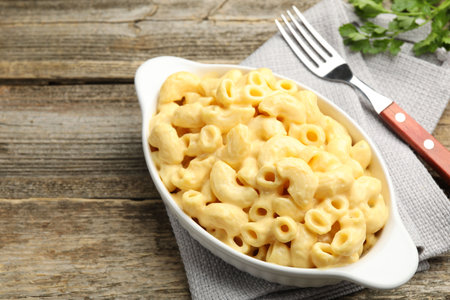 Delicious pasta with cheese sauce, parsley and fork on wooden table, closeup. Space for textの写真素材