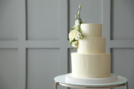 Delicious wedding cake with floral decor on table indoors, space for textの写真素材