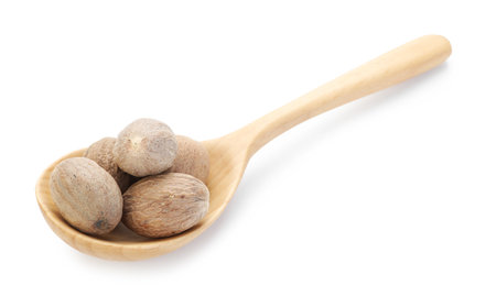 Nutmegs in wooden spoon isolated on whiteの写真素材