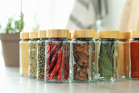 Many different aromatic spices in jars on table indoors, closeup