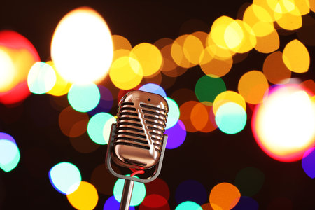 Vintage microphone on dark background with blurred lights, space for text. Musical equipmentの写真素材