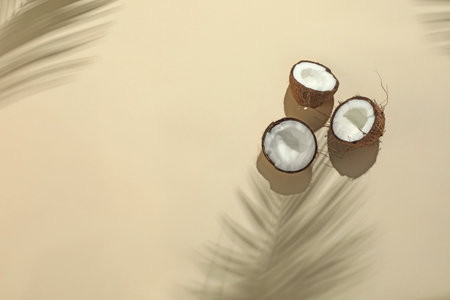 Fresh coconuts and shadow cast by tropical palm on beige background, flat lay. Space for textの写真素材