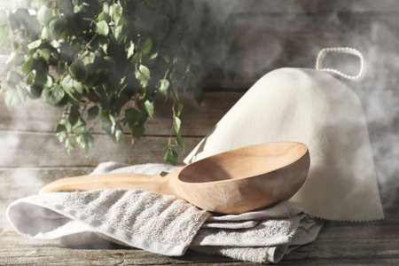 Sauna equipment. Felt wool hat, ladle and towel on wooden surface in steamの写真素材