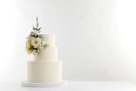 Delicious wedding cake decorated with flowers on table against white background. Space for textの写真素材
