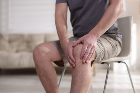 Man suffering from knee pain at home, closeupの写真素材