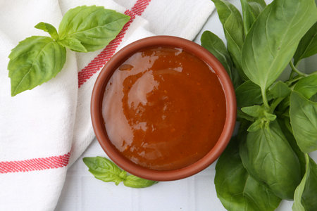 Tasty curry sauce and basil leaves on white tiled table, flat layの写真素材