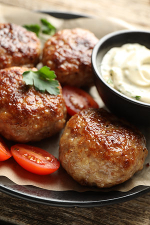 Delicious patties, parsley, tomatoes and sauce on wooden table, closeupの写真素材