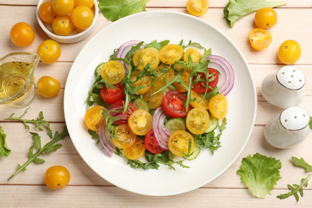 Fresh salad with yellow tomatoes on white wooden table, flat layの写真素材